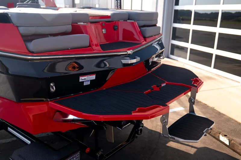 Slide: The Image of 2027 MasterCraft XT24 boat rear view with red and black detailing, featuring a swim platform. - 7