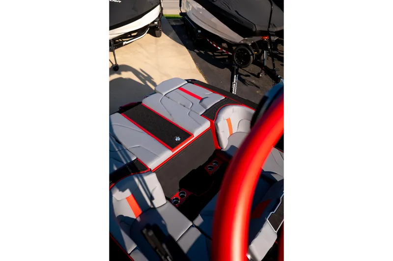 Slide: The Image of 2027 MasterCraft XT24 boat interior with red and gray seating, parked on a trailer. - 33