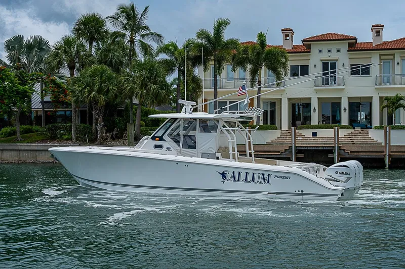 Slide: The Image of 2020 Pursuit S 368 Sport boat cruising near luxury waterfront home with palm trees. - 14