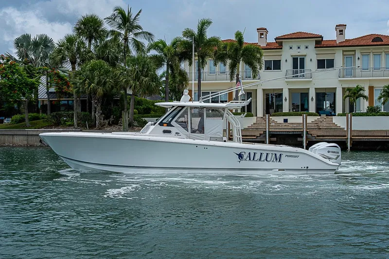 Slide: The Image of 2020 Pursuit S 368 Sport boat cruising near waterfront mansion with palm trees. - 12