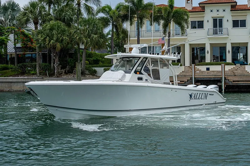 The Image of 2020 Pursuit S 368 Sport boat cruising near waterfront property with palm trees. - 0