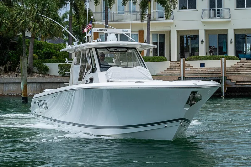 Slide: The Image of 2020 Pursuit S 368 Sport boat cruising near waterfront property with palm trees. - 5
