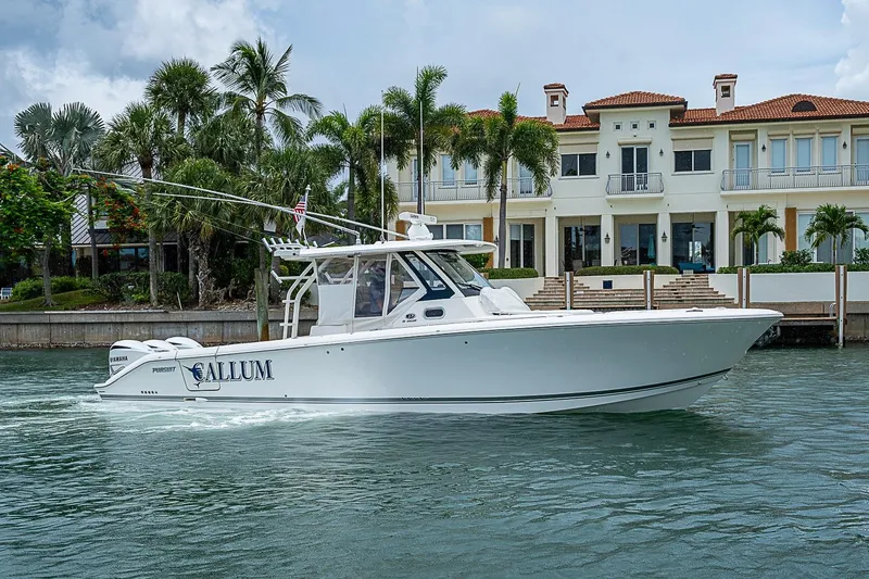Slide: The Image of 2020 Pursuit S 368 Sport boat cruising near a luxurious waterfront mansion. - 2