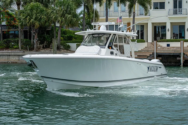 Slide: The Image of 2020 Pursuit S 368 Sport boat cruising near waterfront homes with palm trees. - 8