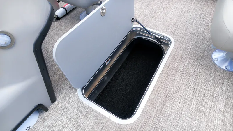 Slide: The Image of An open storage compartment on a boat with carpeted flooring and a gray cover. - 14