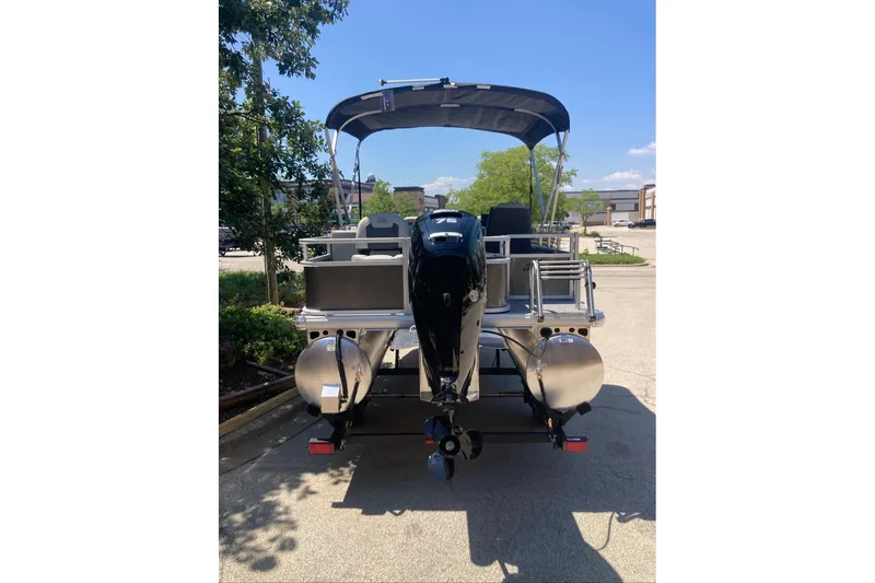 Slide: The Image of 2026 Sun Tracker Bass Buggy 18 DLX pontoon boat, rear view, parked outdoors. - 2