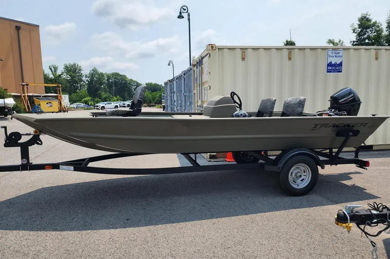 The Image of 2026 Tracker Grizzly 1754 SC boat on trailer, parked outdoors near storage containers. - 0
