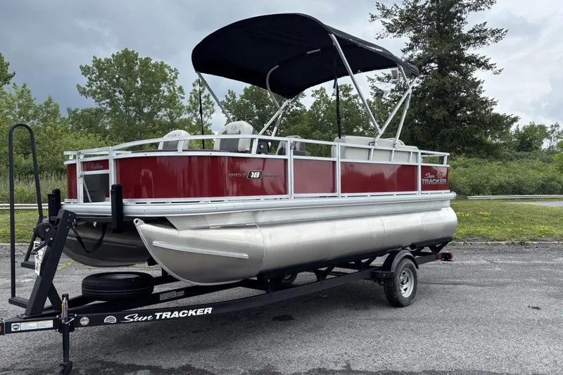The Image of 2026 Sun Tracker Bass Buggy 18 DLX pontoon boat on trailer, parked outdoors. - 0