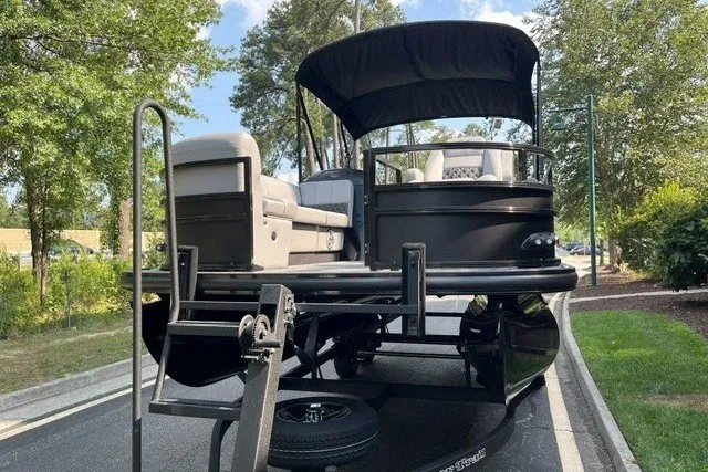 Slide: The Image of 2026 Ranger 220FC pontoon boat on trailer, parked outdoors with canopy and seating visible. - 2