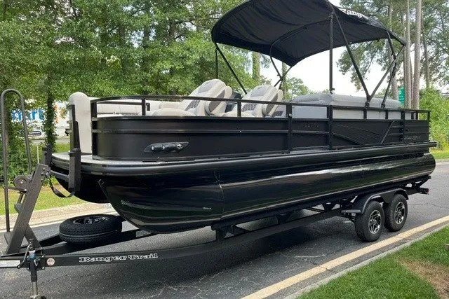 Slide: The Image of 2026 Ranger 220FC pontoon boat on trailer, black exterior, parked outdoors. - 1
