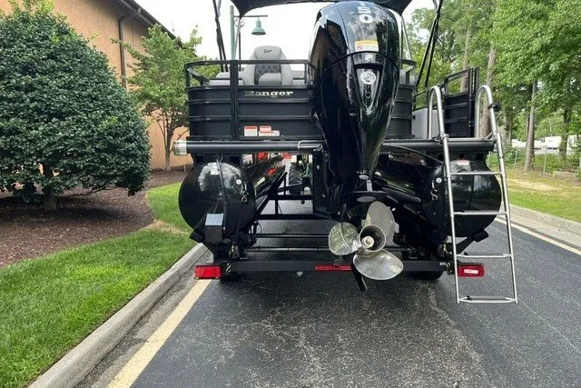 Slide: The Image of 2026 Ranger 220FC boat with dual motors on a trailer, parked near greenery. - 3