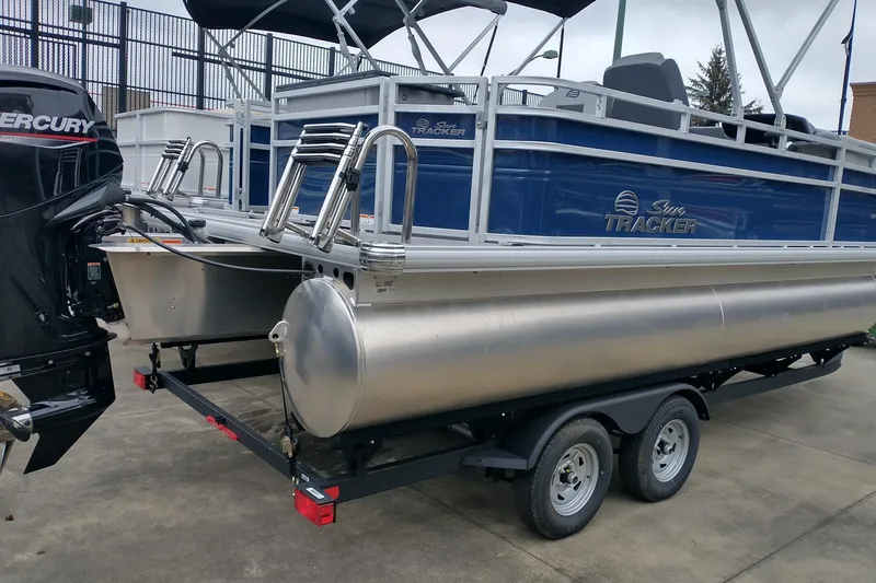 Slide: The Image of 2026 Sun Tracker SportFish 20 DLX pontoon boat on trailer, featuring Mercury engine. - 2