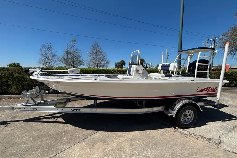 The Image of 2026 Mako 18 Pro Skiff Patriot Edition boat on trailer, parked outdoors under clear blue sky. - 0