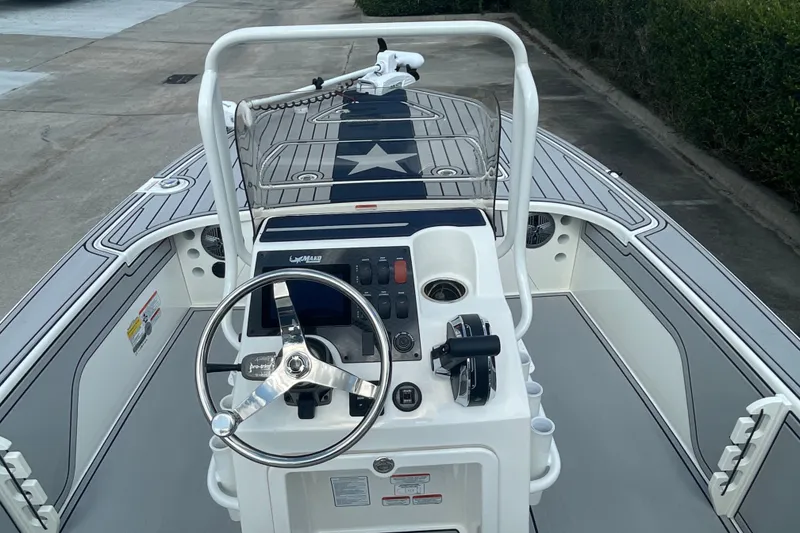 Slide: The Image of 2026 Mako 18 Pro Skiff Patriot Edition boat interior with steering console and star-themed deck. - 13