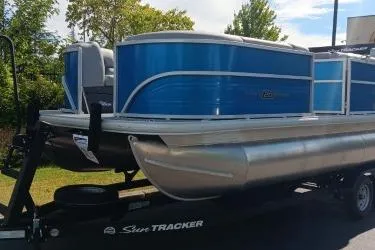 The Image of 2026 Sun Tracker Party Barge 20 DLX pontoon boat on trailer, blue and silver design. - 0