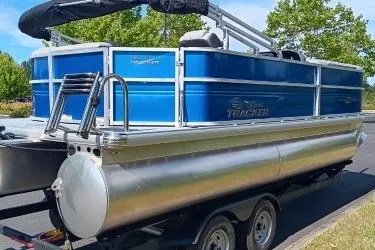 Slide: The Image of 2026 Sun Tracker Party Barge 20 DLX pontoon boat on trailer, blue and silver design. - 3