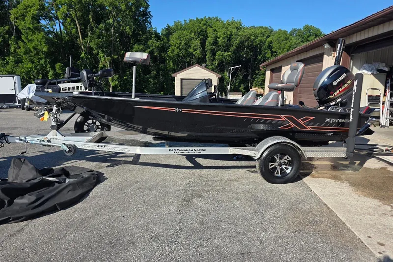 The Image of 2023 Xpress H17 boat on trailer, parked outdoors near garage, surrounded by trees. - 6
