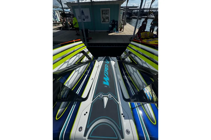 Slide: The Image of 2022 MTI 48 powerboat with vibrant graphics docked near a shop by the water. - 11