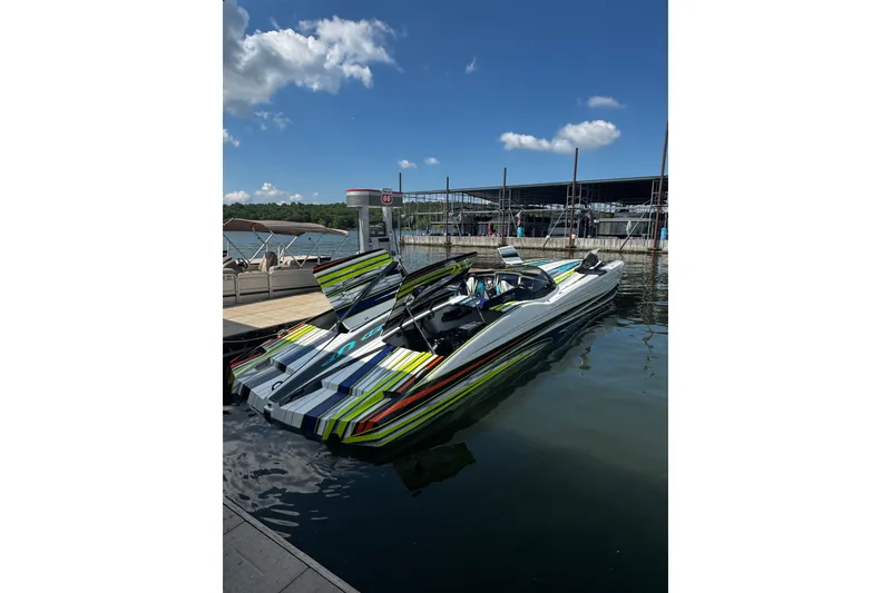 The Image of 2022 MTI 48 speedboat with vibrant stripes docked at a marina under a clear blue sky. - 0