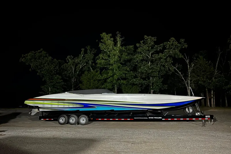 Slide: The Image of 2022 MTI 48 boat on trailer, vibrant colors, parked at night with trees in background. - 8