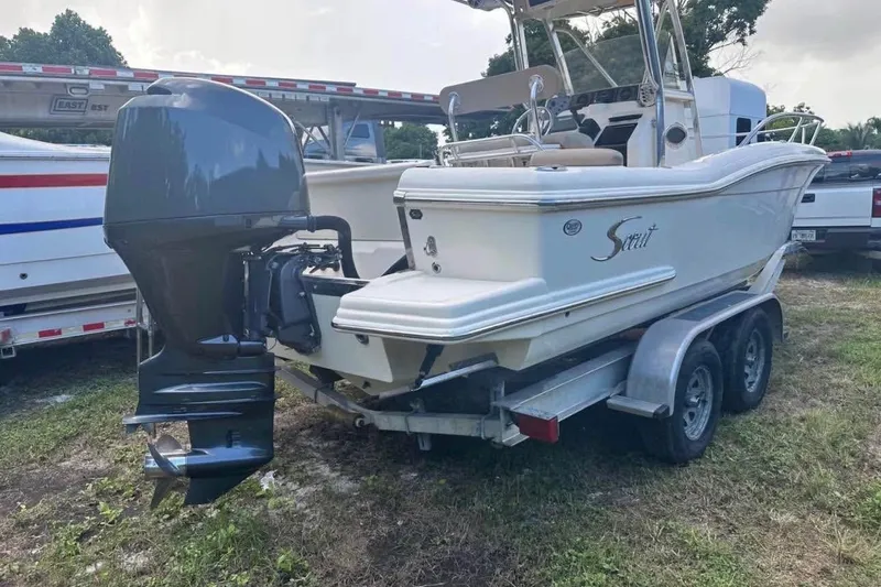 Slide: The Image of 2012 Scout 225 XSF boat on trailer with outboard motor, parked outdoors. - 4