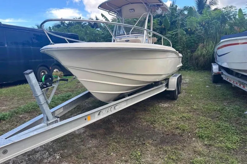 Slide: The Image of 2012 Scout 225 XSF boat on trailer, parked on grassy area with lush greenery. - 2