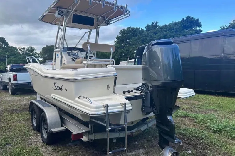 Slide: The Image of 2012 Scout 225 XSF boat on trailer with outboard motor, parked outdoors. - 3
