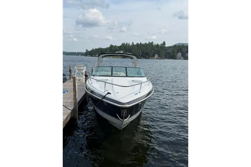 Slide: The Image of 2009 Formula 310 Sun Sport boat docked on a serene lake with forested shoreline. - 2