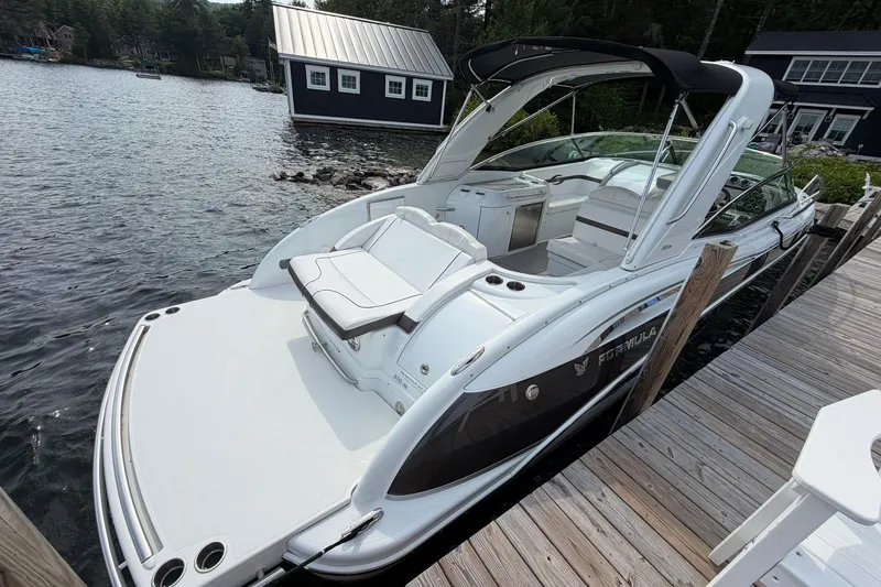 Slide: The Image of 2009 Formula 310 Sun Sport boat docked by a serene lakeside cabin. - 4