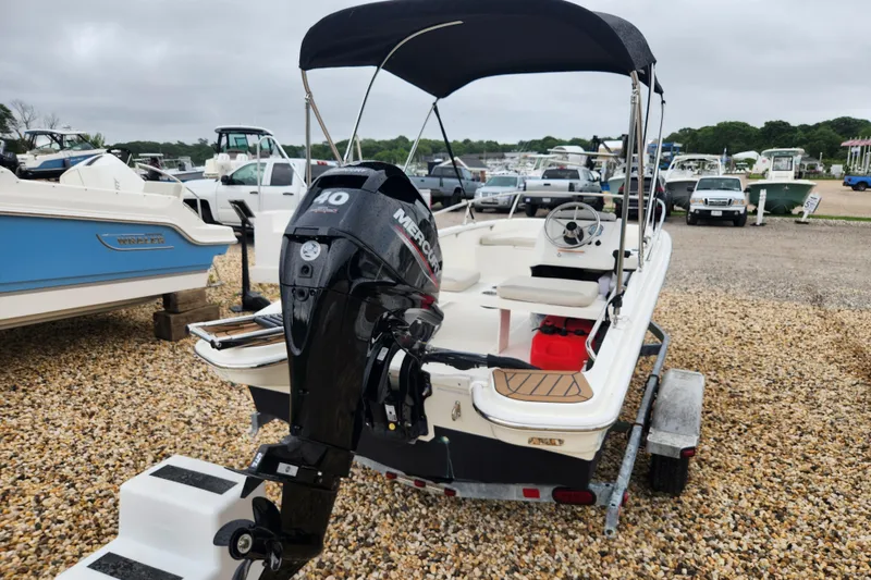 Slide: The Image of 2024 Boston Whaler 130 Super Sport boat with Mercury engine on a gravel lot. - 2