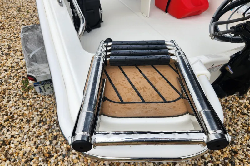 Slide: The Image of 2024 Boston Whaler 130 Super Sport swim ladder on pebble surface. - 3