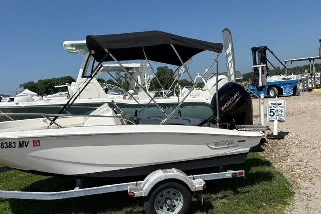 Slide: The Image of 2024 Boston Whaler 130 Super Sport boat on trailer, parked outdoors with canopy. - 3