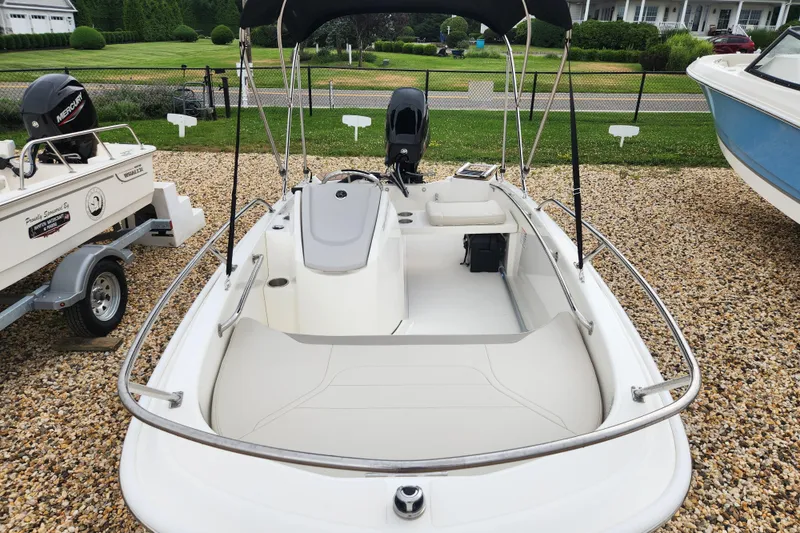 Slide: The Image of 2024 Boston Whaler 130 Super Sport boat with canopy, parked on gravel. - 7