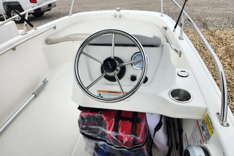 Slide: The Image of 2024 Boston Whaler 130 Super Sport boat interior with steering wheel and dashboard controls. - 5