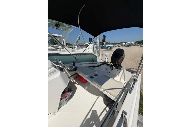 Slide: The Image of 2024 Boston Whaler 130 Super Sport boat interior with seating and motor, parked outdoors. - 4