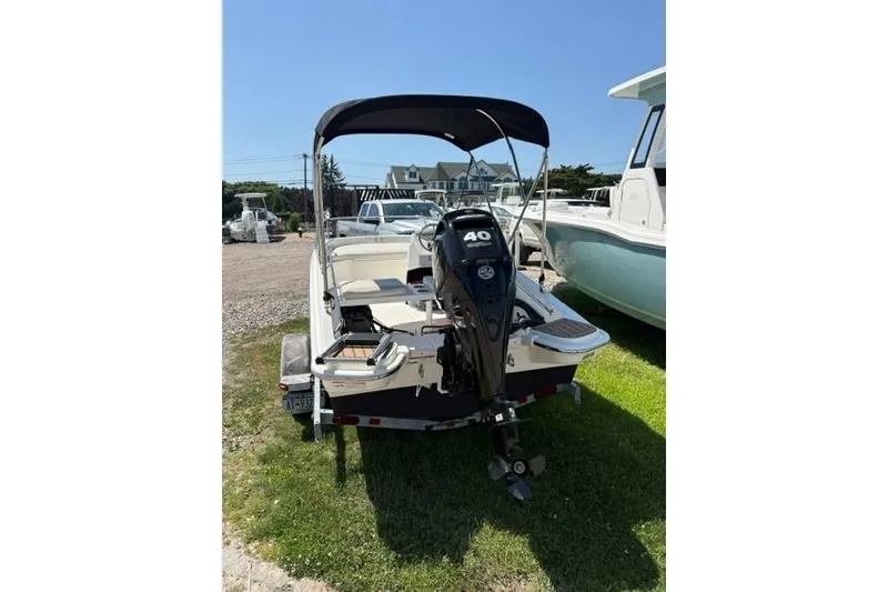 Slide: The Image of 2024 Boston Whaler 130 Super Sport boat with outboard motor, parked on grass. - 1