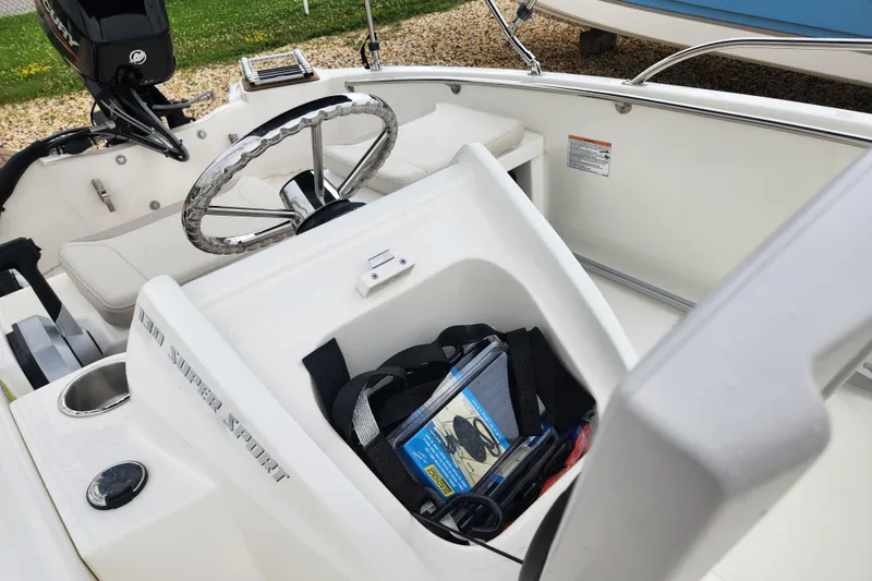 Slide: The Image of 2024 Boston Whaler 130 Super Sport interior with steering wheel and storage compartment. - 6