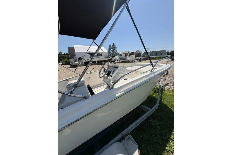 Slide: The Image of 2024 Boston Whaler 130 Super Sport boat with canopy, parked on a trailer. - 7