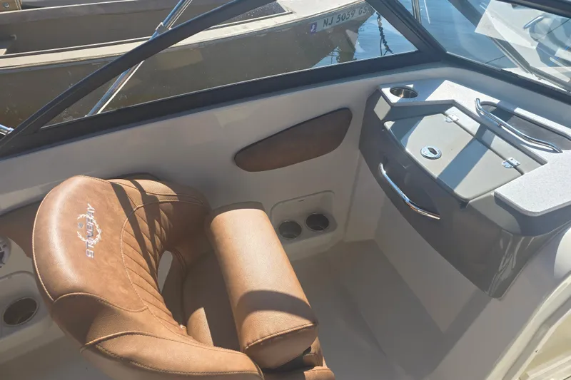 Slide: The Image of 2021 Stingray 201 DC boat interior with brown leather seating and dashboard details. - 7