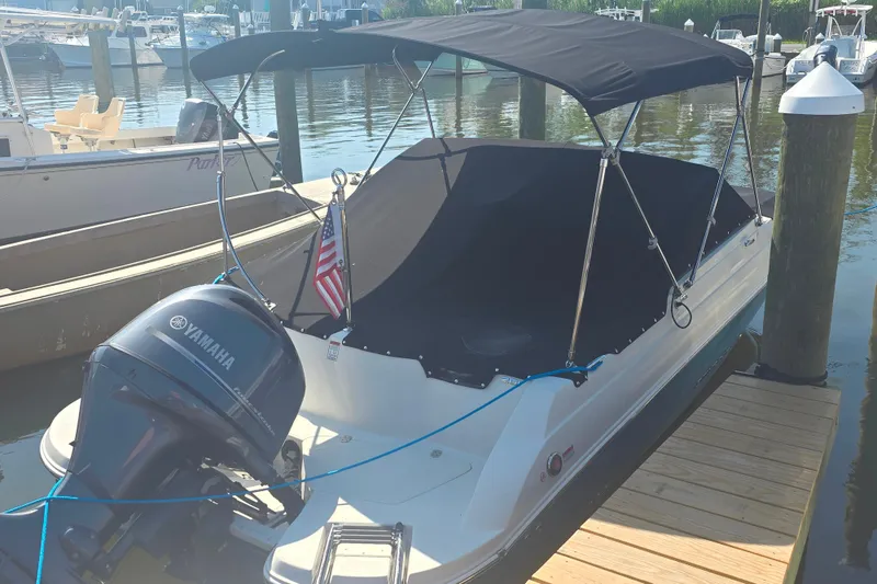 The Image of 2021 Stingray 201 DC boat docked, featuring a Yamaha outboard motor and black canopy. - 2