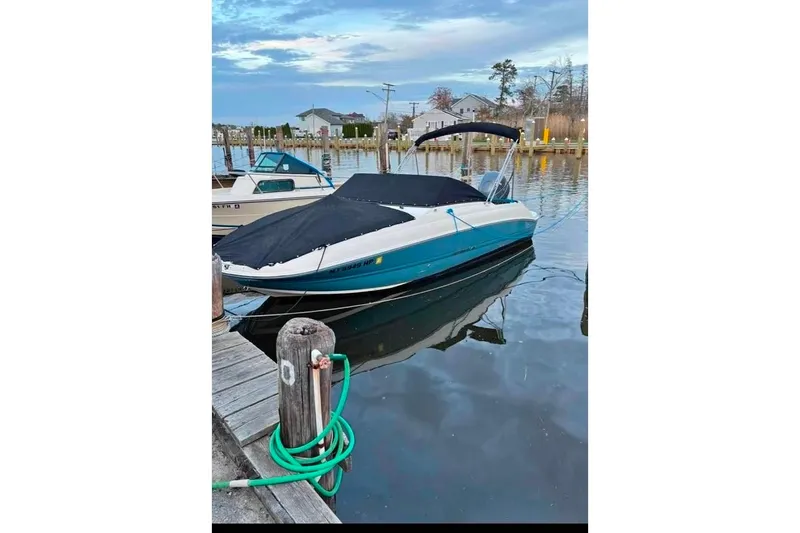 Slide: The Image of 2021 Stingray 201 DC boat docked at a marina, covered and ready for use. - 0