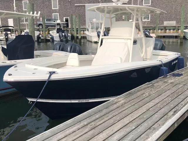 Slide: The Image of A 2019 Regulator 23 Forward Seating boat docked. It features a dark blue hull. - 1