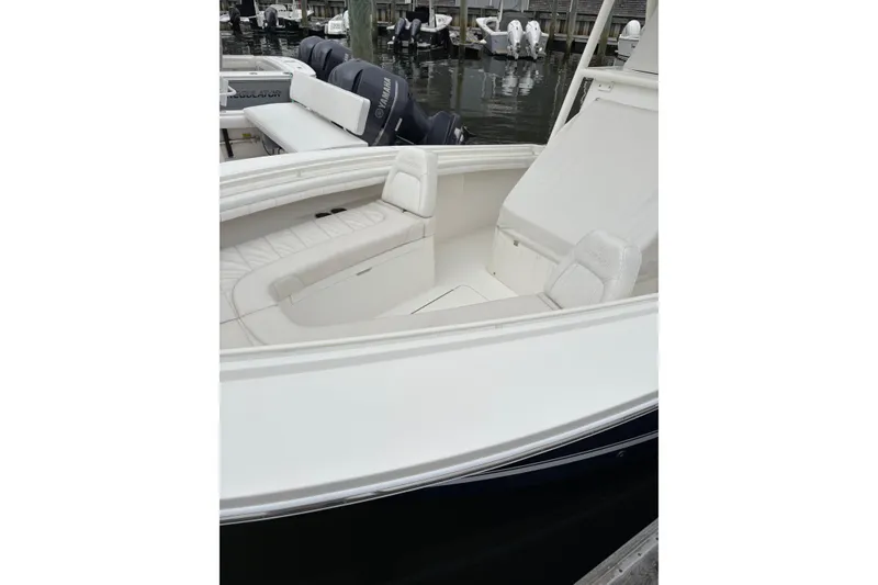 Slide: The Image of 2019 Regulator 23 Forward Seating boat with white cushioned seats, docked near water. - 19