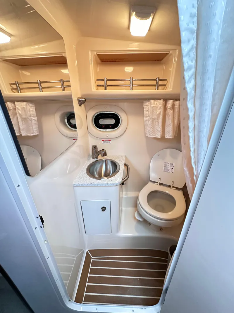 Slide: The Image of 2015 Sea Ray 260 Sundancer bathroom with sink, toilet, and porthole window. - 15