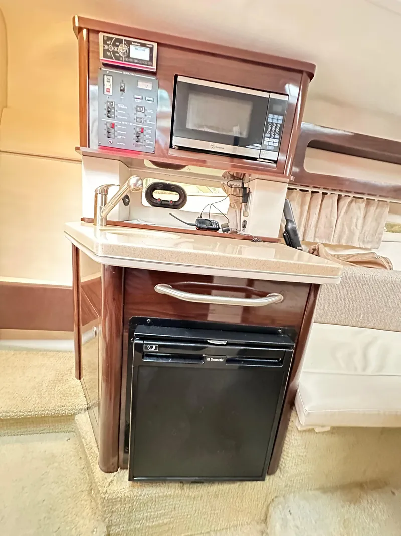 Slide: The Image of 2015 Sea Ray 260 Sundancer interior kitchenette with microwave, sink, and mini-fridge. - 14