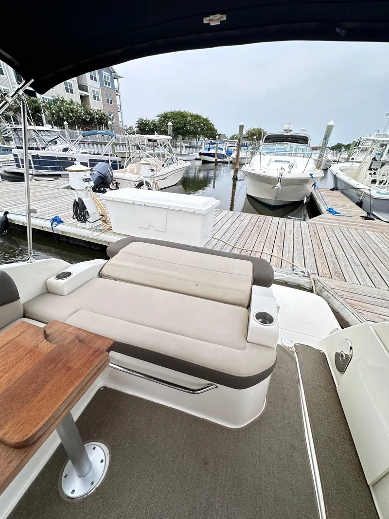 Slide: The Image of 2015 Sea Ray 260 Sundancer at marina, featuring comfortable seating and wooden table. - 6