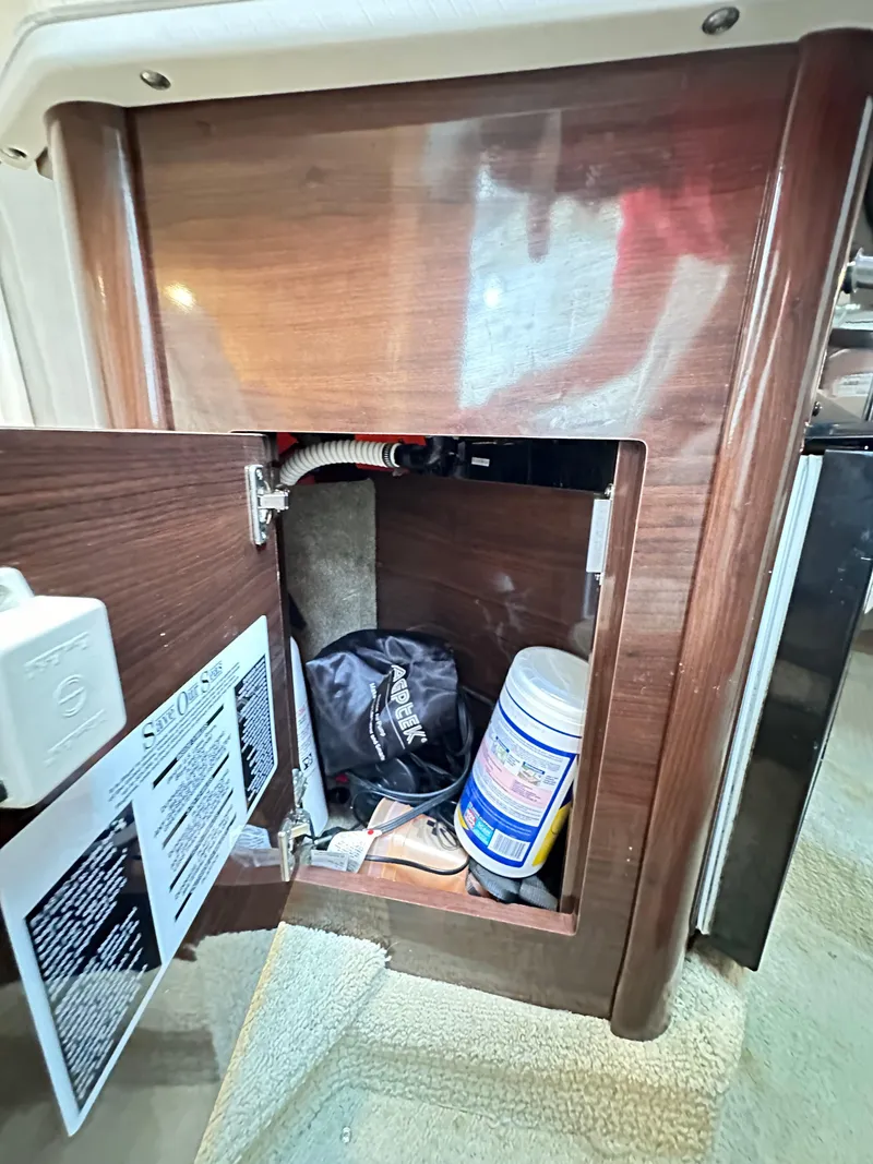 Slide: The Image of 2015 Sea Ray 260 Sundancer interior storage compartment with cleaning supplies and equipment. - 24