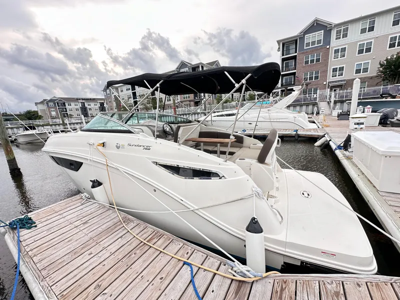Slide: The Image of 2015 Sea Ray 260 Sundancer docked at marina with canopy, residential buildings in background. - 16