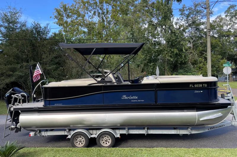 Slide: The Image of 2022 Barletta Cabrio 22QC pontoon boat on trailer, parked outdoors. - 2