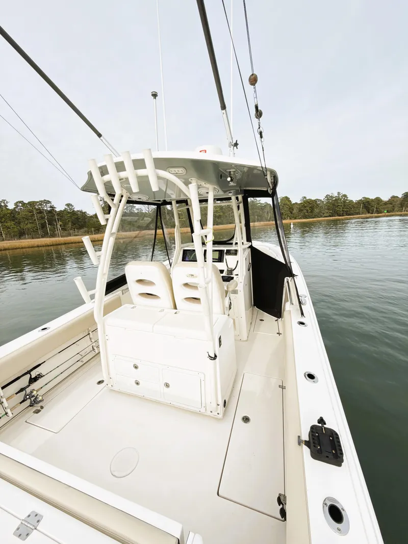 Slide: The Image of 2016 Cobia 296 Center Console boat on calm water, featuring spacious deck and seating. - 8